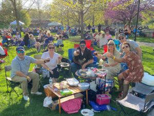 6 people sit and enjoy wine in a park during spring